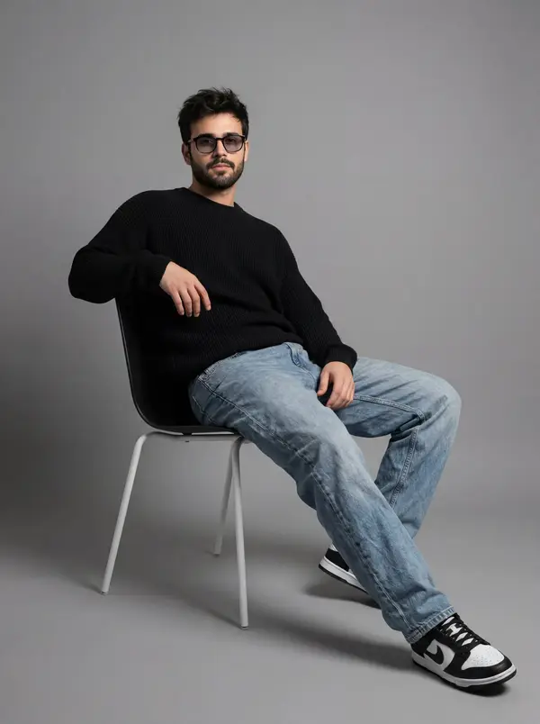 A full-length studio portrait of a young man with dark, messy hair, sitting in… — Nano Banana 2 prompt by @rovvmut_