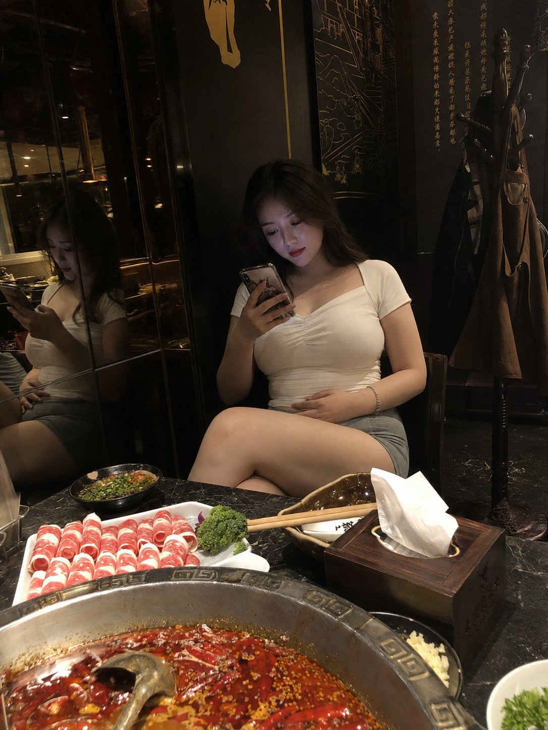 A candid phone photo of a young Chinese woman in her mid-20s sitting in a dimly… — GPT Image 2 prompt by @johnAGI168
