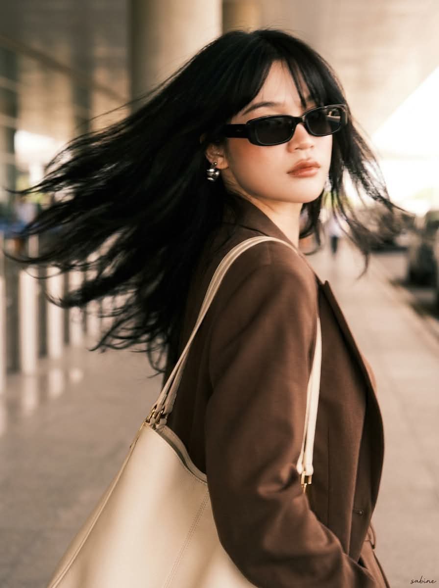 A stylish young woman with long layered black hair and soft curtain bangs,… — Seedream prompt by @ChillaiKalan__