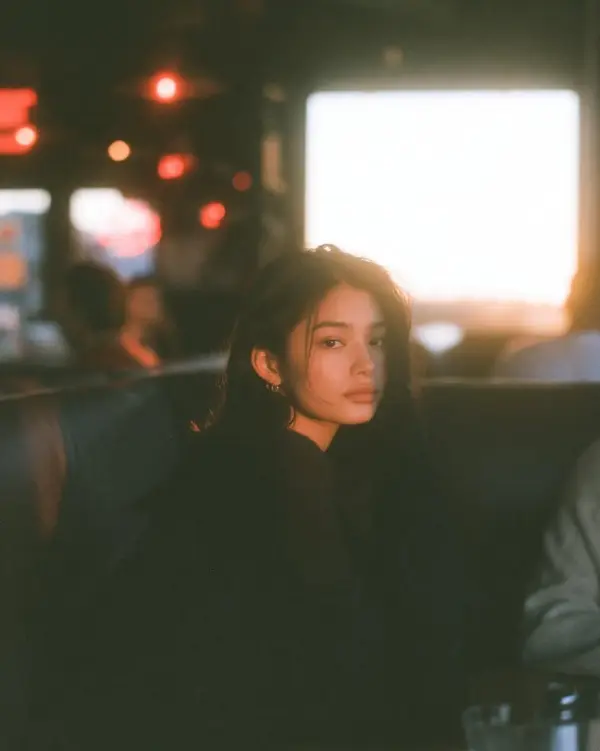 Moody golden hour cafe portrait of a young woman sitting inside a dim… — Midjourney prompt by @Goodmanprotocol