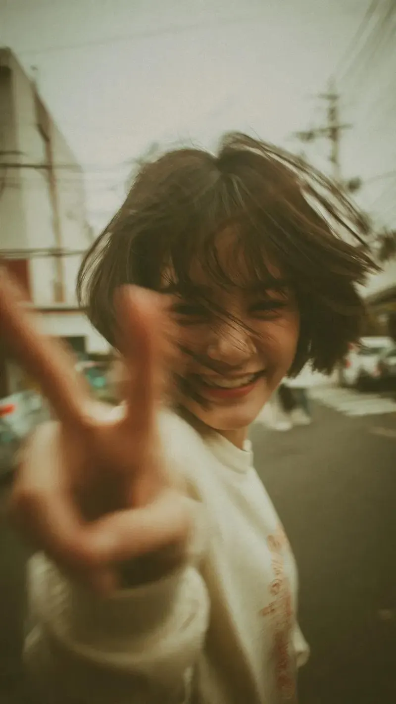 A candid Y2K street photography portrait of a cheerful young woman with a short… — GPT Image 2 prompt by @Taaruk_